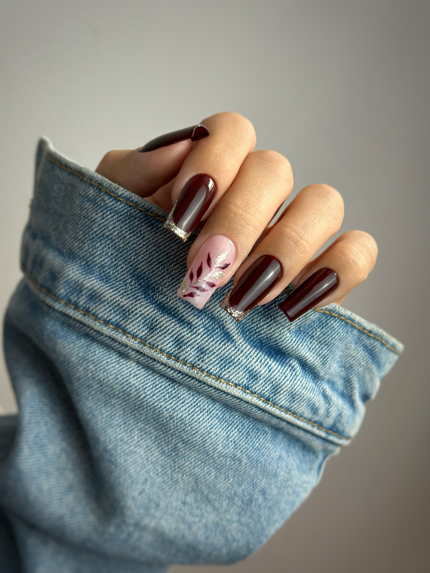 Jesienny manicure w czekoladowym bordo ze złotym frenchem i roślinnymi zdobieniami - zdjęcie 2