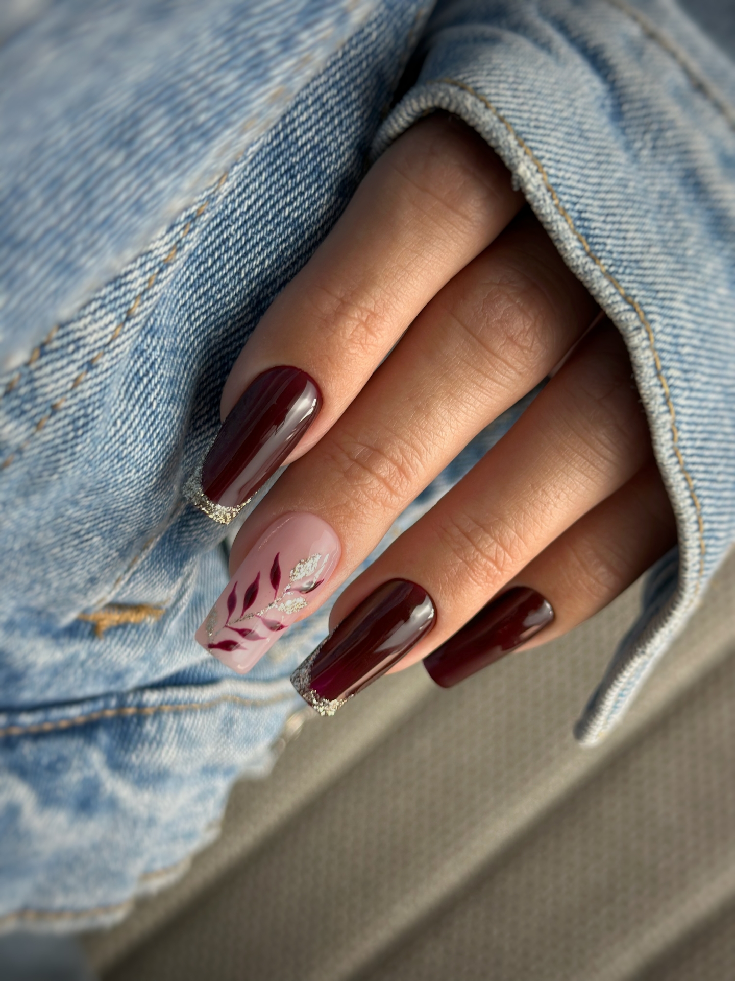 Jesienny manicure w czekoladowym bordo ze złotym frenchem i roślinnymi zdobieniami - zdjęcie 3